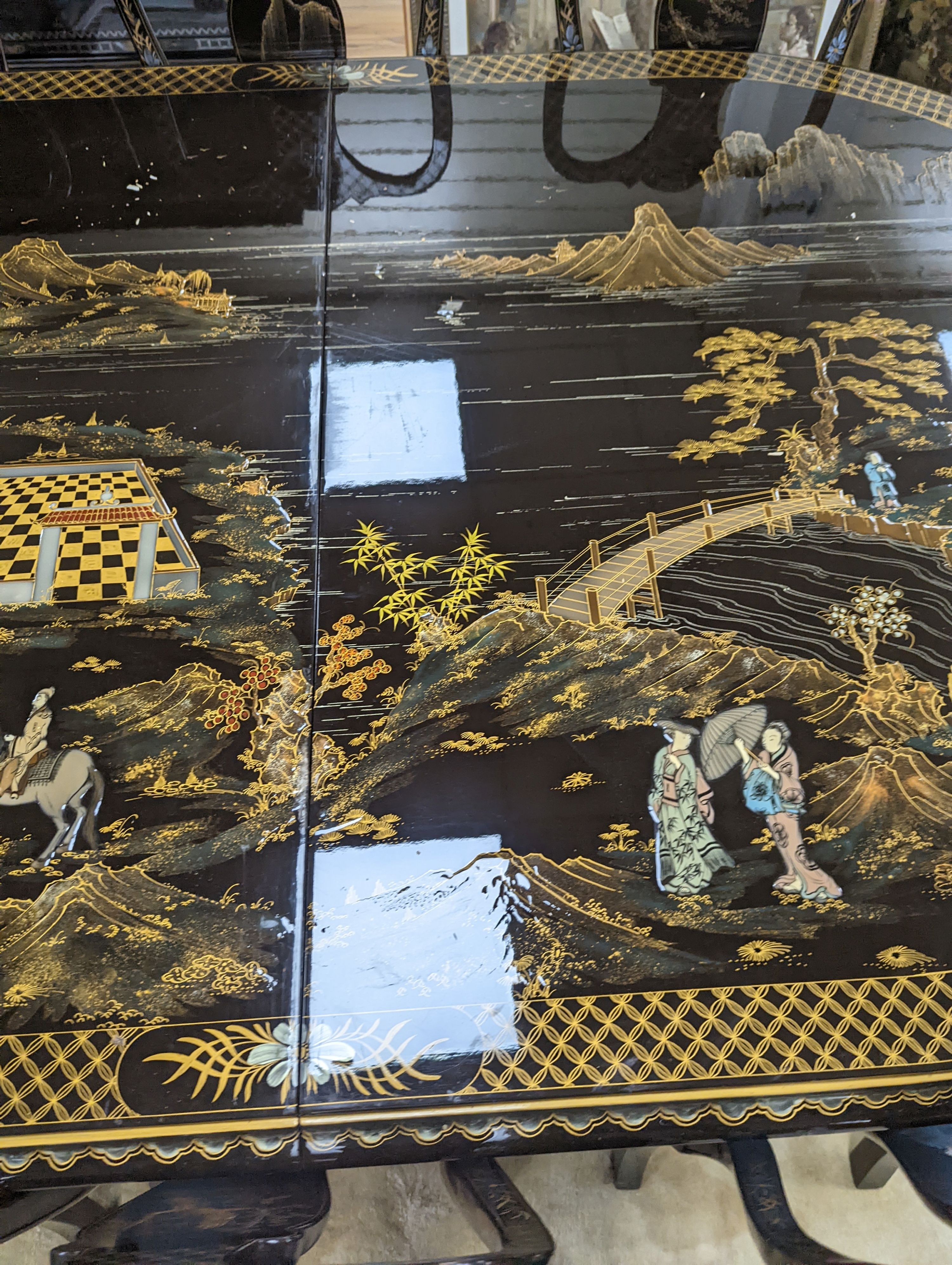 A Chinese lacquer decorated dining table and 12 chairs. Length -277cm, Depth- 120cm, Height - 74cm.